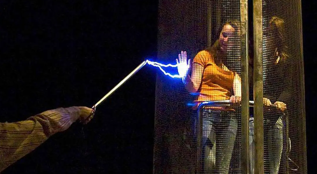 High-voltage demonstration of a person protected inside a conductive Faraday cage